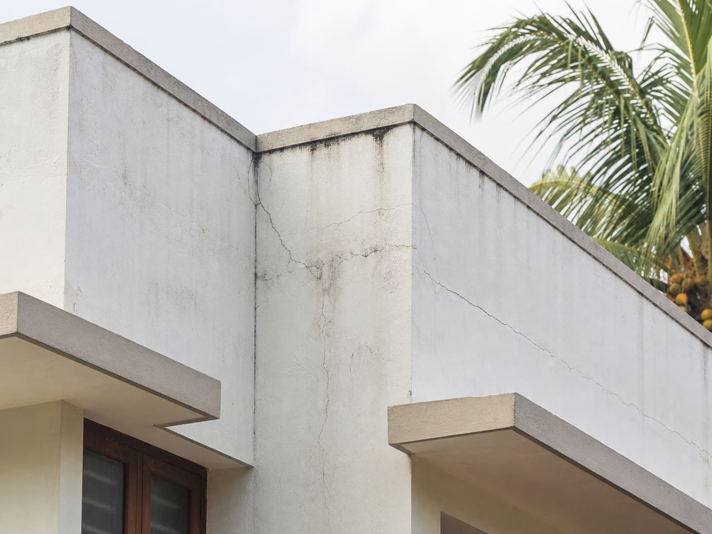 Cracks and faint damp marks at an exterior wall junction