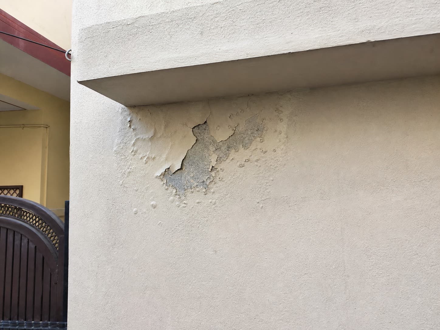 Peeling and bubbling paint below a shaded exterior ledge